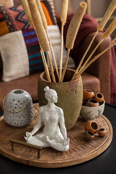 Kadın heykelleri, desenli renkli yastıklar, kurumuş çiçekli vazolar, şamdanlar, ahşap kalıntılar ve kişisel aksesuarlarla birlikte etnik oturma odasının yaratıcı kompozisyonu. Ev dekoru. Şablon.