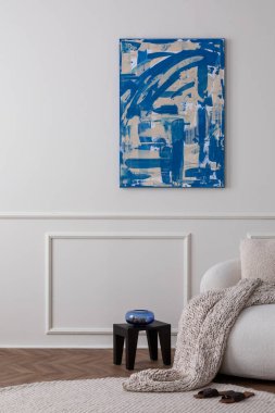 Modern oturma odasının yaratıcı kompozisyonu poster çerçevesi, bej kanepe, yuvarlak halı, kahverengi terlikler, kâseli siyah tabure, örgülü ekose ve kişisel aksesuarlar. Ev dekorasyonu Şablonu