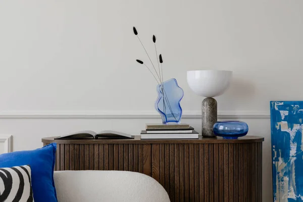 客厅室内有木制餐具柜 有干花的玻璃瓶 大理石灯 白色沙发 蓝色枕头和个人配饰的简约构图 家居装饰 — 图库照片