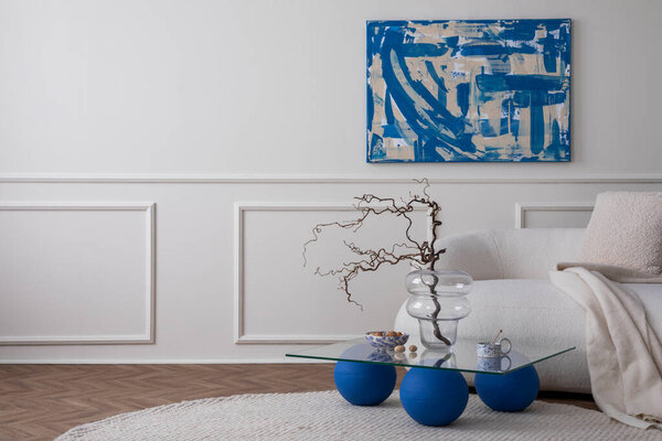 Современная композиция интерьера гостиной с копировальным пространством, макет плакатной рамы, стильный диван, стеклянный журнальный столик, бежевая подушка, миска с орехами, круглый ковер и личные аксессуары. Шаблон домашнего оформления