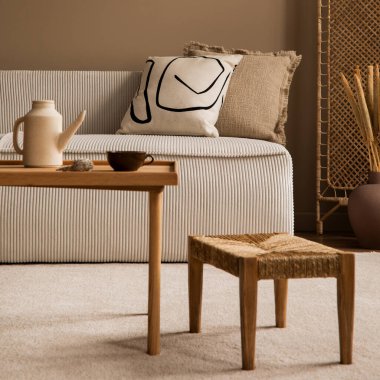 Modüler kanepe, bölme duvarı, ahşap sehpa, yuvarlak yastık, kurumuş çiçekli vazo, rattan lambası ve kişisel aksesuarları olan bir oturma odasının estetik bileşimi. Ev dekoru. Şablon