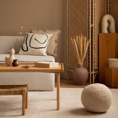 Modüler kanepe, bölme duvarı, ahşap sehpa, yuvarlak yastık, kurumuş çiçekli vazo, rattan lambası ve kişisel aksesuarları olan bir oturma odasının estetik bileşimi. Ev dekoru. Şablon