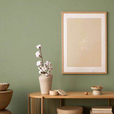 Model poster çerçeveleri, makrome, ahşap çekmece sandığı, bej vazo ve yaratıcı ev aksesuarları olan şık bir oturma odası tasarımı. Bilge yeşil duvar. Şablon. 