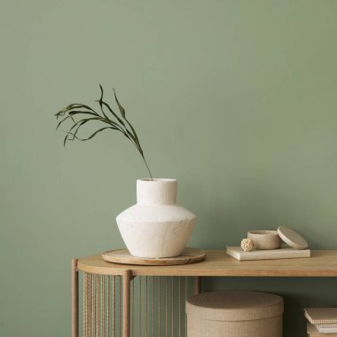 Stylish living room interior design wooden chest of drawers, beige vase and creative home accessories. Sage green wall. Copy space. Template. 