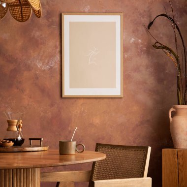 Stylish boho vintage dining room interior with poster mock up. Round table with rattan chair, vase with dried flowers. Brown wall and rattan lamp. Mock up poster. Template. 