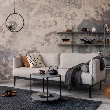 Çatı katı tarzı, gri kanepeli, ekose, halı, sehpa, rattan koltuk ve kişisel aksesuarlı modern bir daire. Gri beton duvar. Ev dekoru. Şablon