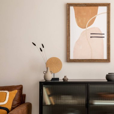 Creative composition of living room interior with mock up poster frame, black commode, lamp on the wooden stand, vase with dried flowers, candle and elegant personal accessories. Home decor. Template.