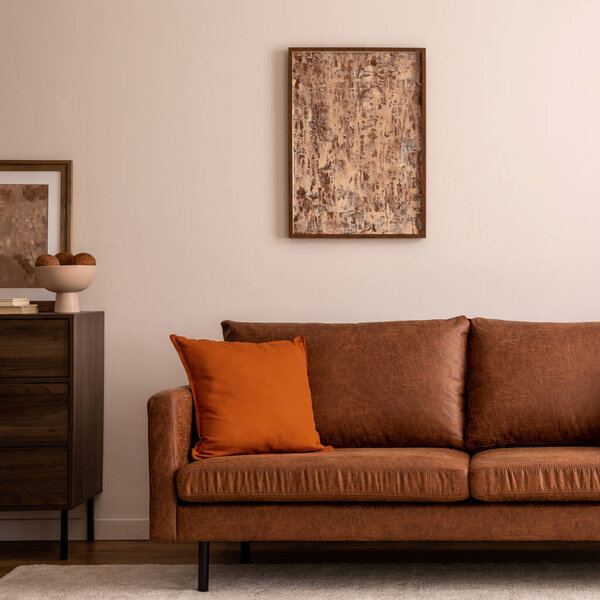 Warm and cozy interior of living room space with brown sofa, beige carpet, lamp, mock up poster frame, decoration, dried flower and coffee table. Cozy home decor. Template.