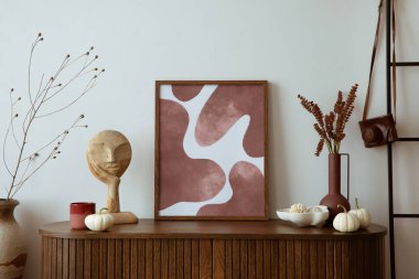 Minimalist composition of living room interior with mock up poster frame, wooden commode, black ladder, vase with dried flowers, wooden sculpture and personal accessories. Home decor. Template.