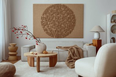 Creative composition of living room interior with mock up poster frame, beige sofa, wooden coffee table, rounded shapes armchair, vase with rowanberry and personal accessories. Home decor. Template.