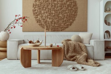 Interior design of japandi living room with mock up poster frame, modular beige sofa, vase with rowan, round wooden coffee table, braided brown plaid and personal accessories. Home decor. Template.