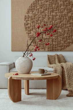Aesthetic composition of living room interior with mock up poster,  modular beige sofa, round coffee table, rug, pouf, bowl, vase with rowan, books and personal accessories. Home decor. Template.