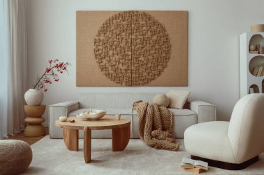 Creative composition of living room interior with mock up poster frame, beige sofa, wooden coffee table, rounded shapes armchair, vase with rowanberry and personal accessories. Home decor. Template.