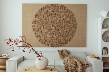Interior design of japandi living room with mock up poster frame, modular beige sofa, vase with rowan, round wooden coffee table, braided brown plaid and personal accessories. Home decor. Template.