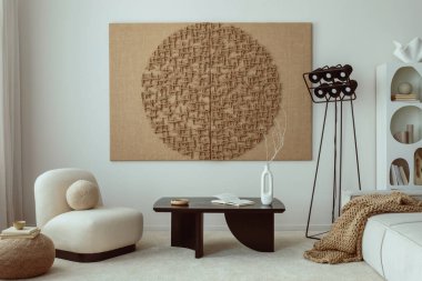 Interior design of living room with mock up poster frame, modern black coffee table, beige sofa, vase with rowan, rounded shapes armchair, pouf. lamp and personal accessories. Home decor. Template.