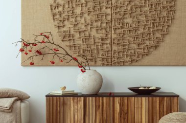 Interior design of japandi living room interior with mock up poster frame, beige vase with rowan, slippers, brown pouf, bowl, books and personal accessories. Home decor. Template.