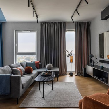 Modern living room interior with gray sofa, black coffee table, orange armchair, big tv, blue and gray curtain, colorful pillows, plaid and personal accessories. Home decor. Template. 