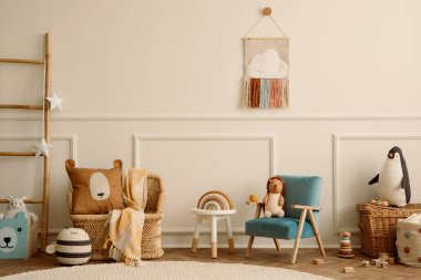 Mavi koltuk, kahve masası, peluş oyuncaklar, bej duvar, sıva, yuvarlak halı, ahşap blok, örülmüş sepet ve kişisel aksesuarlarla oturma odasının yaratıcı bileşimi. Ev dekorasyonu Şablonu