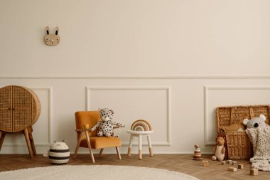 Çocuk odasının minimalist kompozisyonu kadife turuncu koltuk, örgülü sepetler, yuvarlak halı, beyaz tabure, alçılı bej duvar ve kişisel aksesuarlar. Ev dekoru. Şablon.