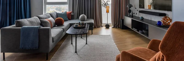 グレーのソファ ブラックコーヒーテーブル オレンジのアームチェア 大きなテレビ 青とグレーのカーテン カラフルな枕 再生され 個人的なアクセサリーを備えたモダンなリビングルームのインテリア 家の装飾だ テンプレート — ストック写真