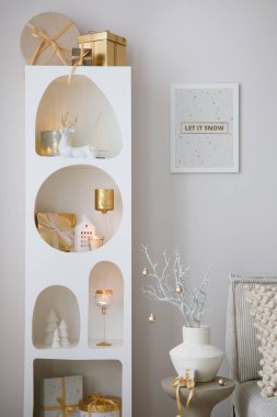 Noel süslemeleri, ışıkları, hediyeleri, fenerleri, geyikleri, mumları, yıldızları ve aksesuarları olan beyaz tasarım rafında güzel bir kompozisyon. Poster çerçevesini düzenle. Noel Baba geliyor. Şablon.