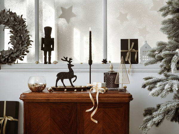 Creative christmas composition on the vintage shelf in the living room interior with beautiful decoration, big window, christmas tree, candles, stars, gifts, light and elegant accessories. Template.