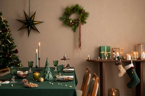 Interior design of warm dinning room interior with christmas table, wooden console, christmas gifts, gingerbread, candle, star on wall christmas wreath and personal accessories. Home decor. Template.