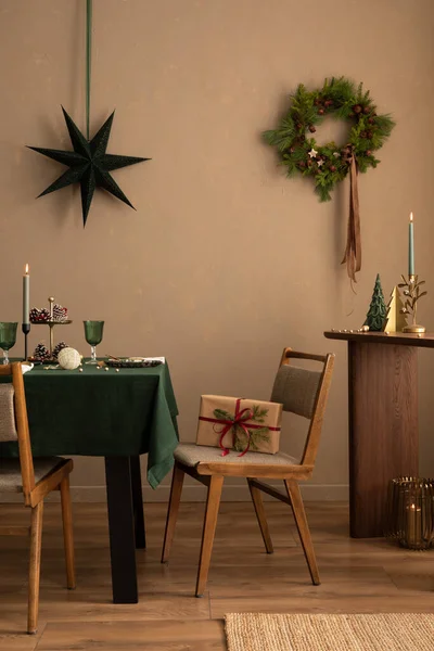テーブル 緑のテーブルクロス 木製のコンソール クリスマスの羽根 ギフト ろうそくが付いているろうそく 成長した壁および優雅な付属品が付いているクリスマスの食堂の内部 ホームデコレーション テンプレート ロイヤリティフリーのストック画像