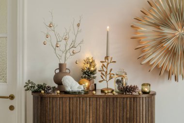 Tatil temalı ahşap dolap. Altın süslemeler, yanan bir mum ve doğal yeşillik de dahil olmak üzere minimalist dekorlarla süslenmiş. Ebedi cazibesi olan samimi bir Noel hediyesi..