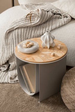 Oturma odasının minimalist kompozisyonu bej kahve masası, şık ahşap panel, kurumuş çiçekli gri vazo, fındıklı ve kişisel aksesuarlı modern kase. Ev dekoru. Şablon.