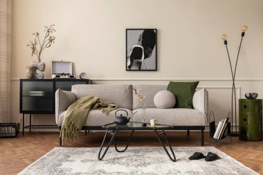 Poster çerçevesi, gri kanepe, siyah kahve masası, desenli halı, saksıdaki bitkiler, terlikler ve kişisel aksesuarlarla dekore edilmiş yaratıcı bir oturma odası kompozisyonu. Ev dekoru. Şablon. 