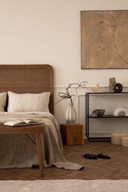 Yatak odasının yaratıcı kompozisyonu poster çerçevesi, rahat yatak, bej yatak, siyah raf, ahşap bank, parlak halı, dallı vazo ve kişisel aksesuarlar. Ev dekoru. Şablon.