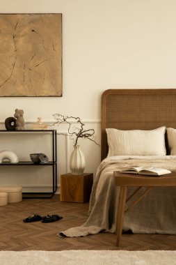 Yatak odasının yaratıcı kompozisyonu poster çerçevesi, rahat yatak, bej yatak, siyah raf, ahşap bank, parlak halı, dallı vazo ve kişisel aksesuarlar. Ev dekoru. Şablon.