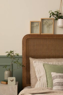 Yatak odasının iç kısmının rahat kompozisyonu poster çerçevesi, şık yatak, bej yatak, lamba, saksıdaki çiçekler, yapraklı vazo, sıva ve kişisel aksesuarlarla kaplı duvar. Ev dekoru. Şablon.