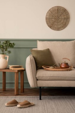 Bej koltuklu, yeşil duvarlı, ahşap sehpalı, kahverengi terlikli, gri yastıklı ve kişisel aksesuarlı yaratıcı bir oturma odası kompozisyonu. Ev dekoru. Şablon. 