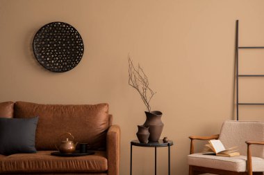 Kahverengi kanepe, küçük koltuk, yuvarlak puf, ahşap büfe, terlikler ve kişisel aksesuarlarla sıcak ve rahat bir oturma odası kompozisyonu. Ev dekoru. Şablon.