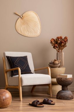 Oturma odasının sıcak ve rahat kompozisyonu gri koltuk, koyu yastık, terlikler, ahşap sehpa, kurumuş çiçekli vazo, kahverengi top ve kişisel aksesuarlar. Ev dekoru. Şablon.