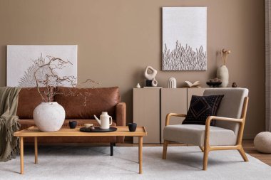 Konforlu oturma odasının iç tasarımı poster çerçevesi, kahverengi kanepe, gri koltuk, ahşap sehpa, bej halı ve kişisel aksesuarlar. Ev dekoru. Şablon. 