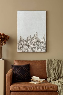 Poster çerçevesi, kahverengi kanepe, desenli yastık, gri ekose, dallı vazo ve kişisel aksesuarları olan rahat oturma odasının estetik kompozisyonu. Ev dekoru. Şablon.