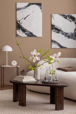 Oturma odasının yaratıcı kompozisyonu poster çerçevesi, boucle kanepesi, ahşap sehpa, yuvarlak halı, beyaz koltuk, manolya ve kişisel aksesuarlar. Ev dekoru. Şablon.