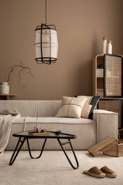 Modüler kanepe, bej duvar, halı, cam sehpa, rattan büfe, terlik, ahşap bank, şık lamba ve kişisel aksesuarlar ile sıcak ve rahat bir oturma odası. Ev dekoru. Şablon.