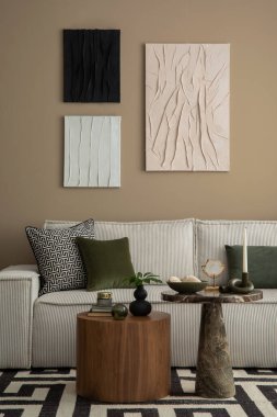 Afiş çerçevesi, modüler kanepe, ahşap sehpa, desenli halı, yeşil yastıklar ve kişisel aksesuarlarla donatılmış zarif oturma odasının estetik yapısı. Ev dekoru. Şablon.