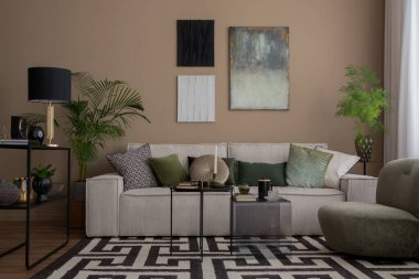 Oturma odasının içinde poster çerçevesi, modüler kanepe, desenli halı, yeşil yastık, cam sehpa, lamba ve kişisel aksesuarları olan yaratıcı bir kompozisyon. Ev dekoru. Şablon. 