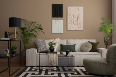 Oturma odasının içinde poster çerçevesi, modüler kanepe, desenli halı, yeşil yastık, cam sehpa, lamba ve kişisel aksesuarları olan yaratıcı bir kompozisyon. Ev dekoru. Şablon. 