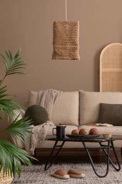 Boho oturma odasının iç dekorasyonu bej kanepe, siyah yuvarlak kahve masası, boho lambası, bölme duvarı, ekoseli sepet ve kişisel aksesuarlarla. Ev dekoru. Şablon.