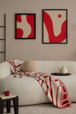 Oturma odasının yaratıcı kompozisyonu poster çerçevesi, bej kanepe, desenli kırmızı ekose, sürahi, merdiven, ahşap tabure ve kişisel aksesuarlar. Ev dekoru. Şablon. 