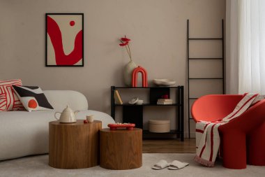 Sıcak ve rahat bir oturma odası. Poster çerçevesi, modern kırmızı koltuk, ahşap sehpa, bej kanepe, terlikler, kurumuş çiçekli vazo ve kişisel aksesuarlar. Ev dekoru. Şablon.