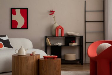 Sıcak ve rahat bir oturma odası. Poster çerçevesi, modern kırmızı koltuk, ahşap sehpa, bej kanepe, terlikler, kurumuş çiçekli vazo ve kişisel aksesuarlar. Ev dekoru. Şablon.