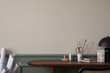 Ahşap masa, koltuk, nane lambası, kitaplar, şık heykeller, kalemler, sıva ve kişisel aksesuarlarla bej ve yeşil duvarlı samimi ofis iç mimarisi. Ev dekoru. Şablon.