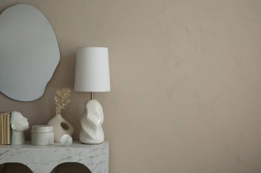 Mermer kemer konsolu, şık lamba, çiçekli bej vazo, şık heykel, cam top ve kişisel aksesuarları olan şık bir oturma odası kompozisyonu. Ev dekoru. Şablon